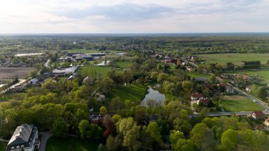 Evleri ve göleti olan küçük bir kasaba manzarası. Gökyüzü bulutlu ve kasaba bir tarlanın ortasında gibi görünüyor. Hava fotoğrafçılığı