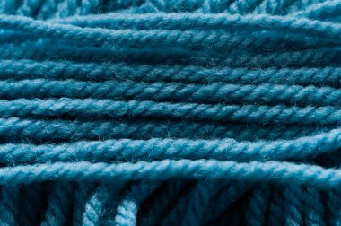 Görüntüde çok düğümlü mavi bir iplik gösteriliyor. İplik sıkıca dokunmuş ve pürüzlü bir dokusu var. Eşsiz bir görünüm veriyor. Düğümler ipliğe saçılmış.