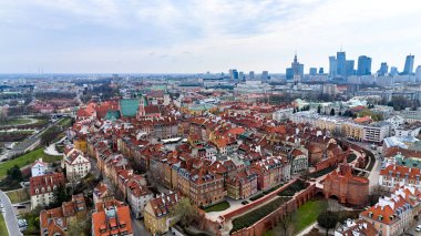 Merkezinde büyük kırmızı bir bina olan şehir manzarası. Binaların çoğu kahverengi ve beyaz. Varşova, Polonya 1-04-2025