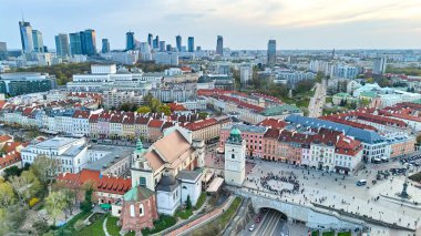 Varşova manzarası. Eski şehrin ortasında büyük bir kalabalık var. Gökyüzü turuncu ve güneş batıyor. İHA görüntüsü. Varşova 13.04.2025, Polonya