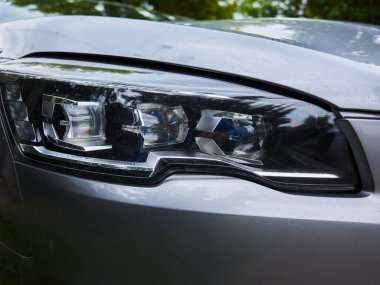 Arabanın farları açık kalmış. Farlar siyah. Araba gümüş rengi.