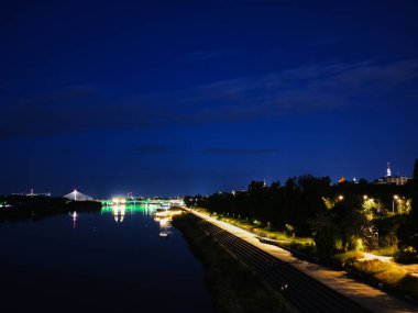 Varşova silueti geceleri ışıldıyor, ortasından bir nehir akıyor. Varşova, Polonya 01.06.2024