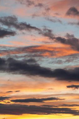 Gökyüzü bulutlarla dolu ve güneş batıyor. Gökyüzü turuncu ve mavi renklerin bir karışımıdır. Telefon duvar kâğıdı. Dikey arkaplan.