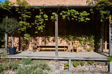 Tahta güverte, bir bank ve iki sandalye. Yedek kulübesi boş. Güverte bir asma duvarıyla çevrili.