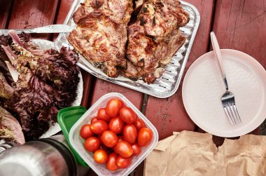 Etli, domatesli, marullu ve çatallı çeşitli yiyecekler. Masada gümüş bir termos da var.