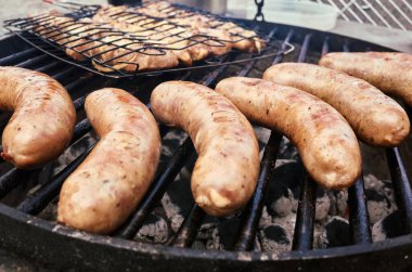 Grill with a rack of hot dogs on it. There are five hot dogs on the grill