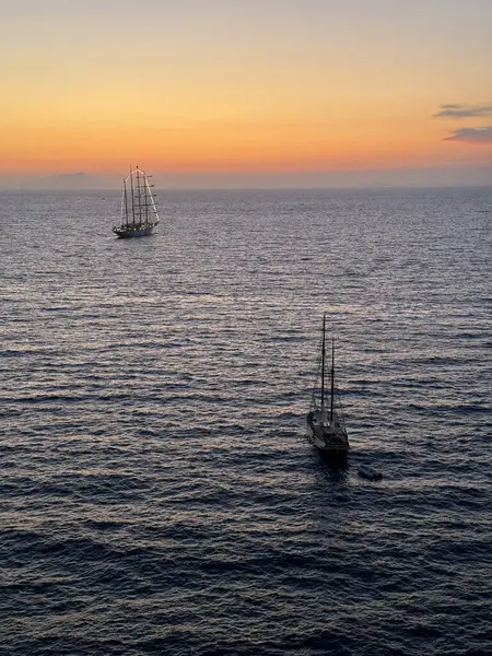 Günbatımında Napoli Körfezi 'ne demir atmış iki büyük yelkenli tekne Sorrento açıklarında. Deniz oldukça sakin ve koyu mavi gökyüzüne karşı kırmızı bir turuncu..