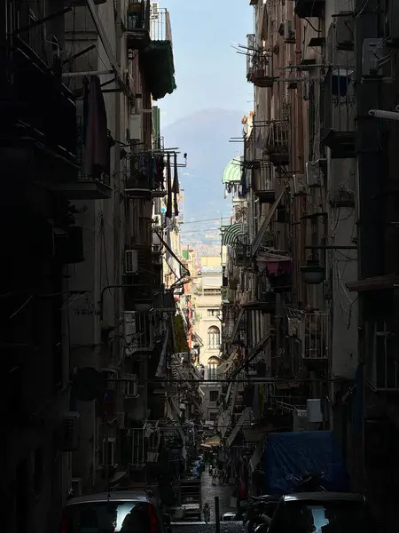 Napoli 'deki İspanyol Mahallesi' nde bir ara sokak, Quartieri Spagnoli. Arka planda Vezüv Dağı var, şehrin üzerinde yükselen volkan. Karanlık dar cadde balkonlarla dolu..