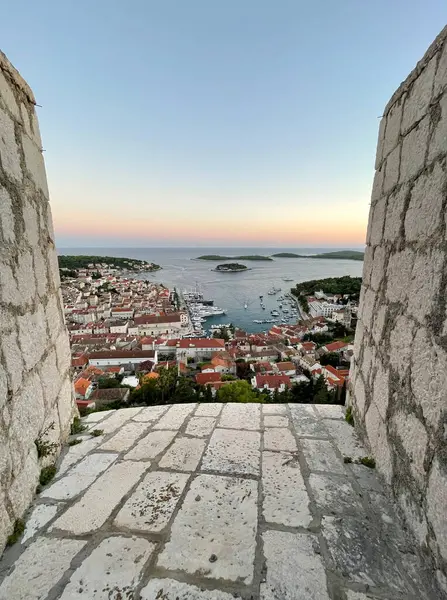 Hırvatistan 'ın Hvar Kalesi' nden bir manzara, Hvar Kasabası 'na tepeden bakıyor. Limanda demirli pahalı yatlar var. Akşam oldu ve ufukta güzel bir gün batımı var..