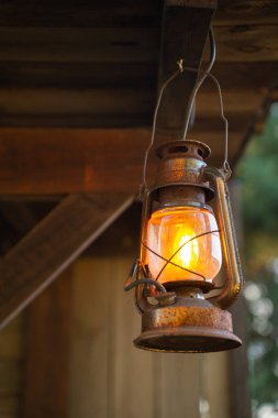 Çatıda eski kahverengi yağ ya da gaz lambası asılı. Klasik sokak lambası. Dikey fotoğraf.