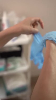 Kozmetik uzmanı ameliyattan önce mavi tıbbi eldiven giyer. Video 4K.