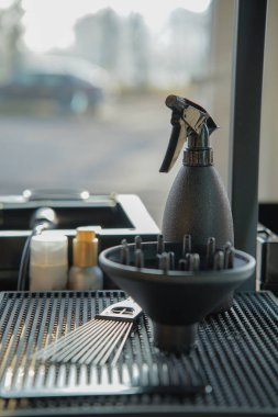 Güzellik salonunda kuaför aletleri masanın üstünde. Yayıcı, tarak, sprey. Kuaför çalışma alanı. Dikey fotoğraf.