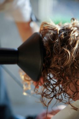 Genç bir kızın kıvırcık saçlarını kuaförde profesyonel bir kuaför şekillendirir. Kıvırcık saçlı CGM 'nin modern metodu.