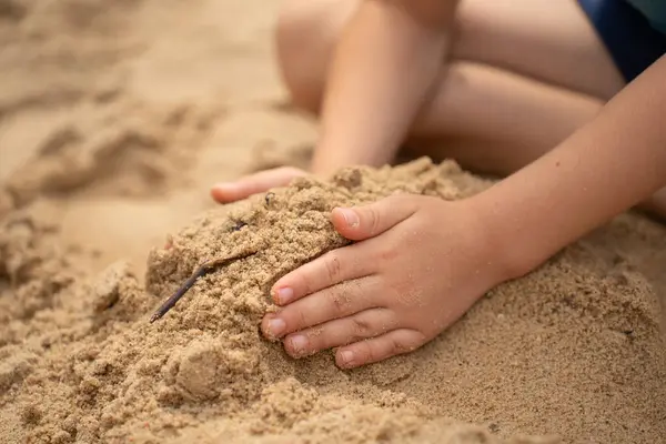 Kum havuzunda oynayan, kum kayakları ve kaleler inşa eden bir çocuğun elleri. Güneşli yaz günü.