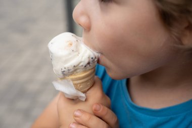 Bir çocuk sıcak bir günde soğuk bir külah erimiş dondurmanın tadını çıkarır. Saf çocukluk sevinci.