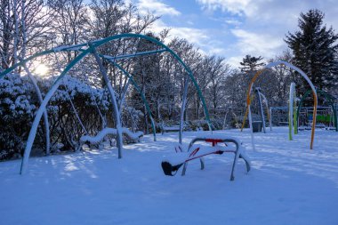 Güneşli kış sabahında kış parkında kar altında donmuş renkli oyun parkı. İskoçya 
