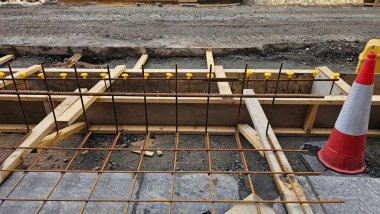 Wooden formwork for pouring concrete from wood for road, piles of steel bars, road red and white cones. Scotland.Works in the city of Aberdeen.High quality photo