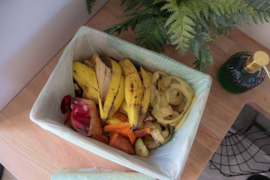 Mutfak tezgahındaki biyolojik poşetteki açık gıda atığının yukarıdan aşağı görüntüsü..