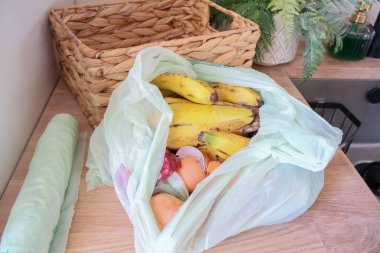 Mutfak tezgahındaki biyolojik poşetteki açık gıda atığının yukarıdan aşağı görüntüsü..