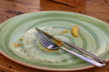 Ahşap yüzey manzarasında çatal ve bıçaklı bir yemekten sonra boş yeşil tabak. Yüksek kalite fotoğraf