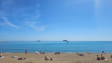 Malaga, İspanya - 26 Mayıs 2022: İspanya 'nın Malaga kentindeki La Malagueta plajı, birçok insanın güneşli bir bahar gününde panoramik bir formatta kumların üzerinde oturup güzel havanın tadını çıkarmasıyla. Yüksek kalite fotoğraf
