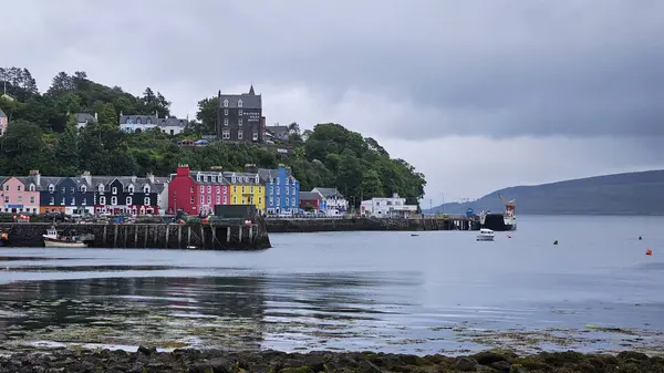 Tobermory, İskoçya 16 Haziran 2024 Tobermory rıhtımındaki renkli evler görülüyor. Dalgalar çekildi. Gri Gök. Yüksek kalite fotoğraf