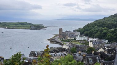  Oban İskoçya. 16 Haziran 2024 Havadan kasaba ve liman manzarası. Dağılmış ağaçlar, arka planda deniz. Gri gökyüzü Yüksek kalite fotoğraf