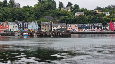 Tobermory, İskoçya 16 Haziran 2024 Tobermory rıhtımındaki renkli evler görülüyor. Dalgalar çekildi. Gri Gök. Yüksek kalite fotoğraf