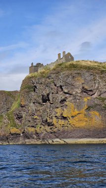 Deniz kenarından manzara. DUNNOTTAR Şatosu, SCOTLAND Kuzey Denizi kıyısındaki kayalık bir burunda bulunan ortaçağ kalesi Dunnottar Kalesi 'ni harap etti. İskoçya 'daki sarp okyanus kayalıklarının tepesinde görkemli bir kale..