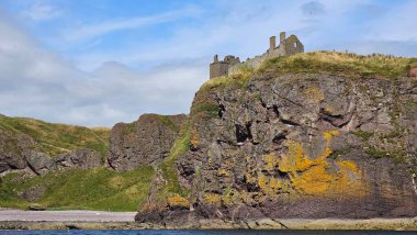 Deniz kenarından manzara. DUNNOTTAR Şatosu, SCOTLAND Kuzey Denizi kıyısındaki kayalık bir burunda bulunan ortaçağ kalesi Dunnottar Kalesi 'ni harap etti. İskoçya 'daki sarp okyanus kayalıklarının tepesinde görkemli bir kale..