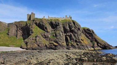Deniz kenarından manzara. DUNNOTTAR Şatosu, SCOTLAND Kuzey Denizi kıyısındaki kayalık bir burunda bulunan ortaçağ kalesi Dunnottar Kalesi 'ni harap etti. İskoçya 'daki sarp okyanus kayalıklarının tepesinde görkemli bir kale..