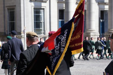 İskoçya 'nın Aberdeen kentinde düzenlenen Silahlı Kuvvetler Günü Geçit Töreni sırasında üniformalı gaziler arkadan yürüyordu. Arka plan, halkın kutlamalarının bir parçası olan disiplinli hareketlerini ve törensel başlıklarını vurguluyor.