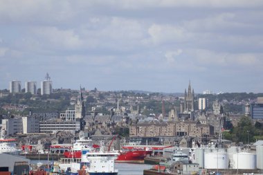 Aberdeen Limanı 'nın panoramik görüntüsü, çok sayıda gemi ve liman altyapısı ile dolup taşıyor. Arka plandaki şehir silueti 2025 'te gerçekleşecek olan Uzun Gemiler etkinliğinde, liman hazırlıklarını ve önemini vurguluyor.