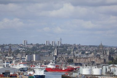 Aberdeen Limanı 'nın panoramik görüntüsü, çok sayıda gemi ve liman altyapısı ile dolup taşıyor. Arka plandaki şehir silueti 2025 'te gerçekleşecek olan Uzun Gemiler etkinliğinde, liman hazırlıklarını ve önemini vurguluyor.