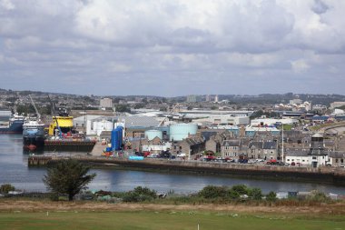 Aberdeen Limanı 'nın panoramik görüntüsü, çok sayıda gemi ve liman altyapısı ile dolup taşıyor. Arka plandaki şehir silueti 2025 'te gerçekleşecek olan Uzun Gemiler etkinliğinde, liman hazırlıklarını ve önemini vurguluyor.