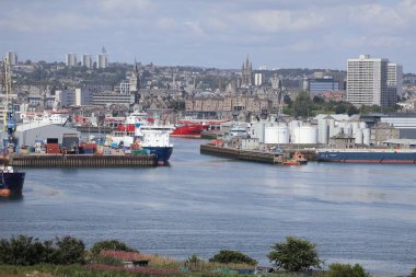 Aberdeen Limanı 'nın panoramik görüntüsü, çok sayıda gemi ve liman altyapısı ile dolup taşıyor. Arka plandaki şehir silueti 2025 'te gerçekleşecek olan Uzun Gemiler etkinliğinde, liman hazırlıklarını ve önemini vurguluyor.