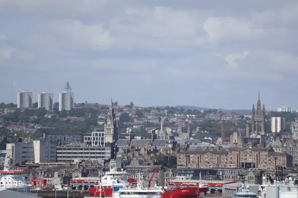 Aberdeen Limanı 'nın panoramik görüntüsü, çok sayıda gemi ve liman altyapısı ile dolup taşıyor. Arka plandaki şehir silueti 2025 'te gerçekleşecek olan Uzun Gemiler etkinliğinde, liman hazırlıklarını ve önemini vurguluyor.