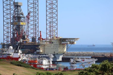 Aberdeen Limanı 'nın panoramik görüntüsü, çok sayıda gemi ve liman altyapısı ile dolup taşıyor. Arka plandaki şehir silueti 2025 'te gerçekleşecek olan Uzun Gemiler etkinliğinde, liman hazırlıklarını ve önemini vurguluyor.