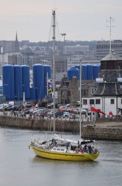 Muhteşem James Cook Uzun Gemisi mürettebatı güneşli bir günde zarif bir şekilde Aberdeen Limanı girişinden geçiyor. Tarihi gemi, İskoç kıyı şeridinin arka planına karşı önemli bir görüntüdür..