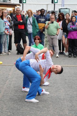 Sokak sanatçıları, İskoçya 'nın Aberdeen kentinde düzenlenen Uzun Gemiler Festivali sırasında kalabalık bir caddede yaptıkları gösteriyle hevesli bir kalabalığı cezbediyor. Küçük bir tekne aksesuarının yer aldığı canlı sahne, deniz olayının canlı atmosferine ekleniyor.