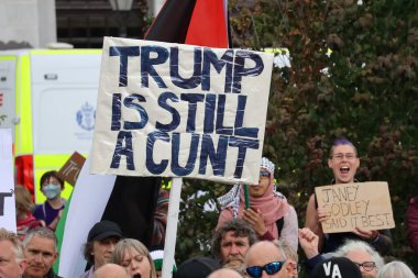 Aberdeen 'deki bir gösteri sırasında yeşil yapraklar arasında yaşayan kişilerin güçlü Trump karşıtı tutumlarını gösteren bir protesto tabelasının yakın çekimi. Bu işaretler merkezi. Trump ziyareti sırasında kamuoyunun yoğun görüşünü yansıtıyor.. 