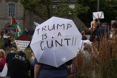 Aberdeen 'deki bir gösteri sırasında yeşil yapraklar arasında yaşayan kişilerin güçlü Trump karşıtı tutumlarını gösteren bir protesto tabelasının yakın çekimi. Bu işaretler merkezi. Trump ziyareti sırasında kamuoyunun yoğun görüşünü yansıtıyor.. 