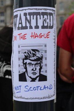 Bir protesto sırasında sokak lambasına Donald Trump 'ın karikatürünün yer aldığı İskoçya değil, Lahey' de Aranıyor posteri asıldı. İmajın merkezinde yer alan işaret, kalabalığın arasında güçlü siyasi duyguları yansıtıyor.
