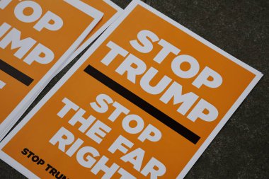 TROP TRUMP SCOTLAND 'ı bir gösteride durdurun mesajını içeren parlak turuncu ve beyaz protesto işareti. Yakın plan, etkinlik sırasında bu siyasi açıklamanın çift odaklı olduğunu vurguluyor.