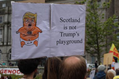 Protesto yazısında, İskoçya 'nın Donald Trump' ın bebekliğinin hicivli bir karikatürünün yanında Trump 'ın oyun alanı olmadığı yazıyor. Görüntü, Aberdeen 'deki cumhurbaşkanlığı ziyareti sırasında kamuoyunun görüşünü yansıtan güçlü bir siyasi muhalefet oluşturuyor..