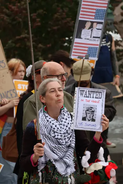 Bir protesto sırasında sokak lambasına Donald Trump 'ın karikatürünün yer aldığı İskoçya değil, Lahey' de Aranıyor posteri asıldı. İmajın merkezinde yer alan işaret, kalabalığın arasında güçlü siyasi duyguları yansıtıyor.