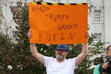 Adamın biri elinde turuncu protesto tabelası tutuyor ve 