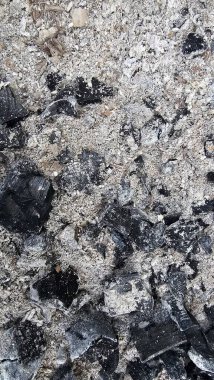 Gri küllerin ve siyah kömürün detaylı dokusu, barbekü veya yangından sonra yanmış ahşap kalıntıları. Soyut desenli doğal bir arka plan. Ekoloji, yıkım, felaket, yanma veya yeniden doğuş kavramı Gri küller ve siyah kömür parçalarını yakın plan