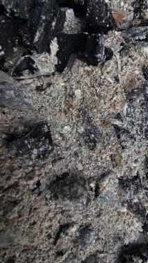 Gri küllerin ve siyah kömürün detaylı dokusu, barbekü veya yangından sonra yanmış ahşap kalıntıları. Soyut desenli doğal bir arka plan. Ekoloji, yıkım, felaket, yanma veya yeniden doğuş kavramı Gri küller ve siyah kömür parçalarını yakın plan