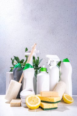 Çevre dostu organik temizlik konsepti. Çevre dostu temizlik aletleri - eko fırçalar, aletler süngerler, doğal temizlik ürünleri, soda, sabun, limon, sirke, beyaz arka planda yeşil yapraklı şişeler